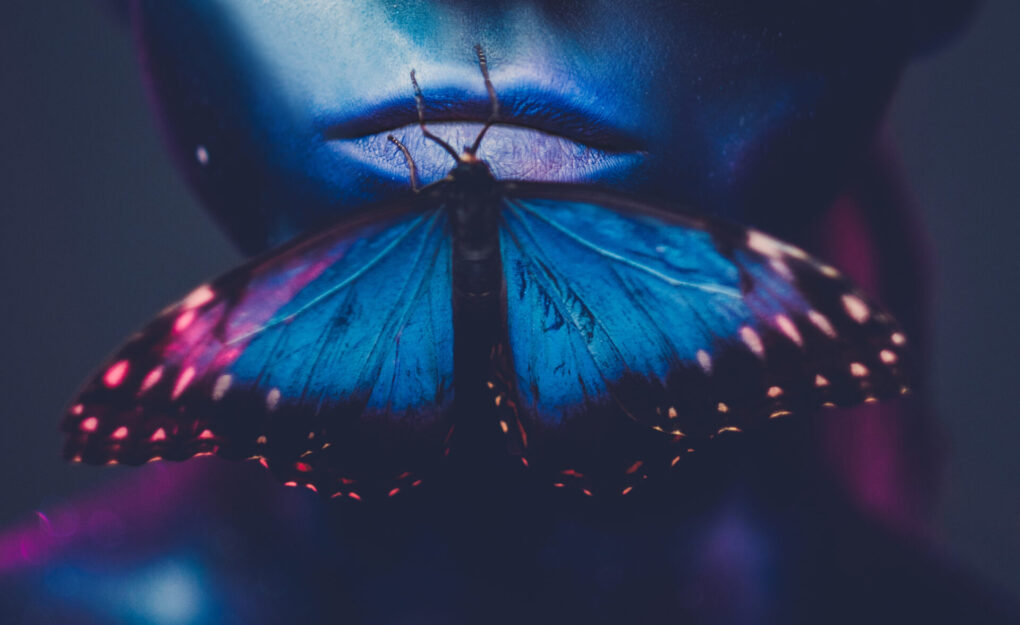 Beautiful woman with butterfly on mouth